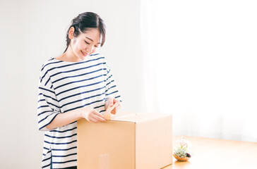 段ボールを開ける女性（笑顔）
