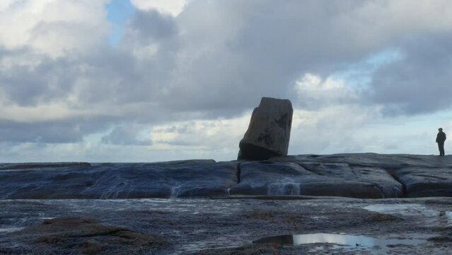 a man walks on the rocks close to the blowhole but manages to avoid getting wet