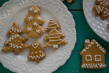 Painted traditional Christmas gingerbreads arranged on white plates on old vintage painted table, various xmas shapes