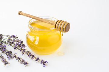 Honey in the glass jar  and lavender flower on the white background. Closeup. Copy space.