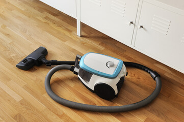 Blue vacuum cleaner on the parquet floor in the living room.