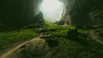 FPV shot of green gours leading to the cave entrance