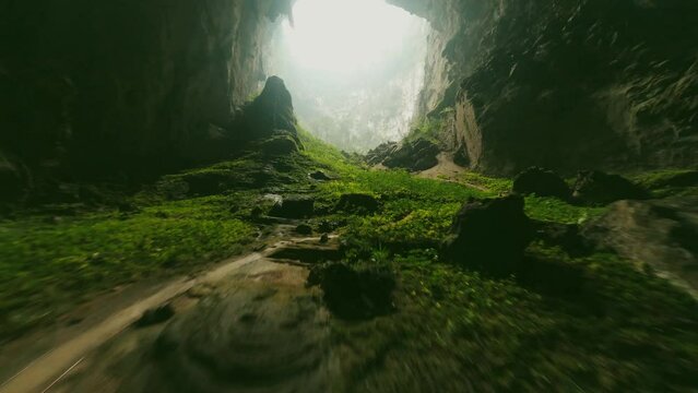 FPV shot of green gours leading to the cave entrance
