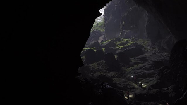 Pan upward shot of tiny explorers in big cave