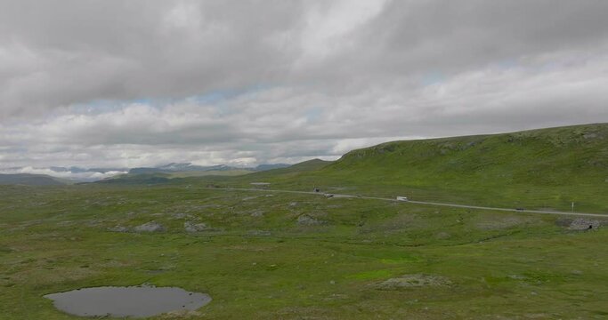 Green landscape of Hardanger Plateau in Norway, road cutting through; drone