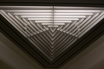 Triangular lamp in interior. Design of lighting device. Lamp on ceiling.
