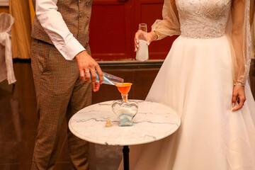 Obraz na płótnie Canvas The bride and groom pour salt into a vessel.
