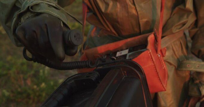Soldier in a protective suit checks the case for radioactivity. Close-up shot
