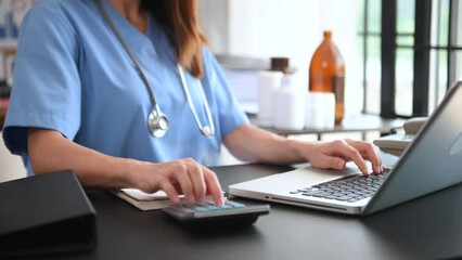 Healthcare costs and fees concept.Hand of smart doctor used a calculator and laptop, tablet for medical costs at hospital - Powered by Adobe