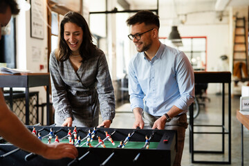 Colleagues having fun at work. Businessman and businesswoman playing table soccer..