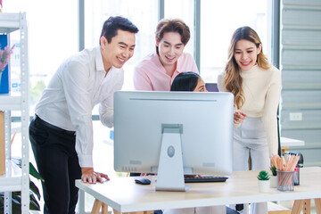 Millennial Asian beautiful successful professional businesswoman sitting smiling pointing finger showing data information on computer monitor to male businessmen female colleague in company office