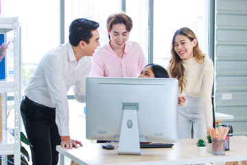 Fototapeta na wymiar Millennial Asian beautiful successful professional businesswoman sitting smiling pointing finger showing data information on computer monitor to male businessmen female colleague in company office