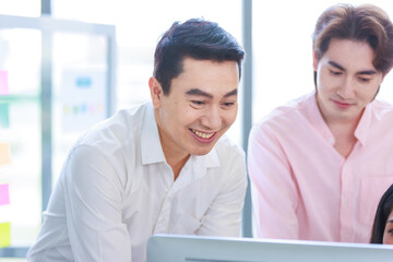 Millennial Asian beautiful successful professional businesswoman sitting smiling pointing finger showing data information on computer monitor to male businessmen female colleague in company office