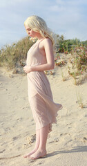 full length portrait of beautiful young woman with long hair wearing simple dress flowing in wind,...