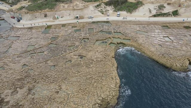 Top aerial view of chequerboard of rock-cut saltpans in the island of Gozo, Malta.