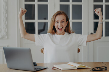 Excited woman gestures power working on project online from home. Concept of win and success.