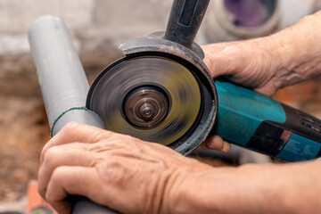 A craftsman cuts a PVC pipe using an x-angle grinder