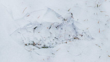 The imprint of a human foot on the ice-covered snow