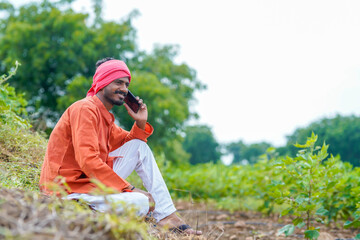 Indian farmer talking on smartphone at agriculture field.