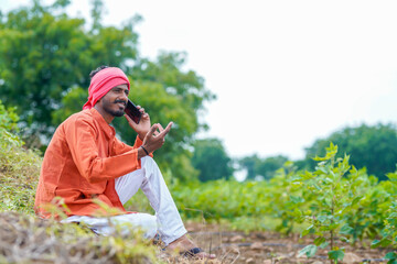 Indian farmer talking on smartphone at agriculture field.