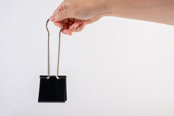 Hand and black paperclip on white background.