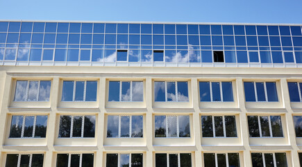 Clouds reflected in windows of modern office building. Exterior of modern building on a sunny day with a blue sky