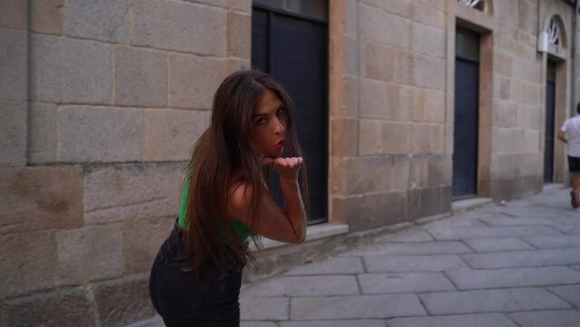 beautiful tourist girl walking forwards in the streets of Spain looking to camera sending a kiss