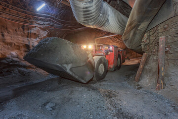 Bulldozer works in dark tunnel of kimberlite mine.