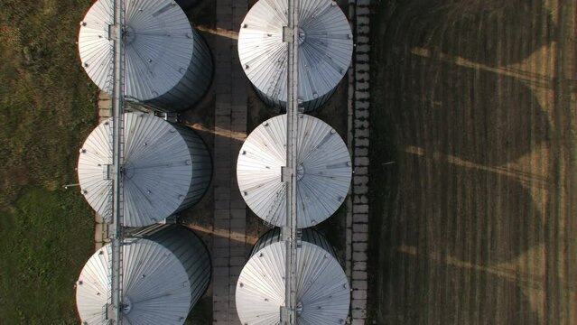 Aerial wide slide shot of agricultural grain silo storage tanks. Top down view