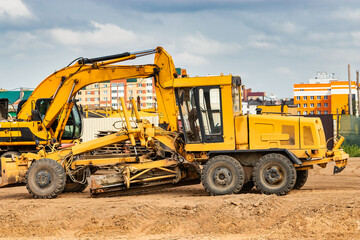 Road grader at the construction site. Powerful construction machine for ground leveling and excavation. Close-up. Professional construction equipment.