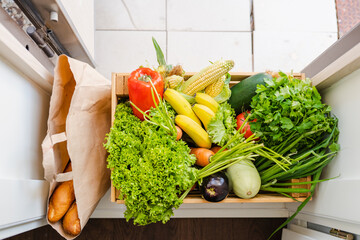Wooden box full of fresh vegetables, fruits and greens stand on doorstep of house, package of...