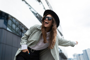 young stylish woman catches a taxi with her hand outstretched against the backdrop of an office building
