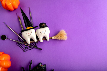 
dental concept. figurines of teeth in halloween costumes and dental instruments. pumpkins and a broom.on a purple background