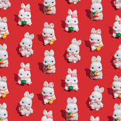Seamless pattern made of little white rabbits on vibrant red background. Symbol of the Chinese New Year of the rabbit. Happy 2023 and good luck!