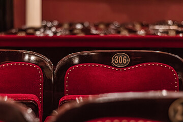 Empty cinema hall with red seats and number plates in cinema on blurred background.