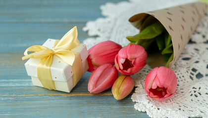 Gift box with long pink ribbon and tulips on wooden background