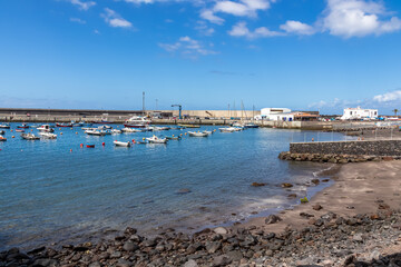 Fototapeta na wymiar Scenic view on the small port of Vueltas seen from Playa de Vueltas in Valle Gran Rey on La Gomera, Canary Islands, Spain, Europe. Small boats are floating in the blue lagoon bay on a sunny summer day