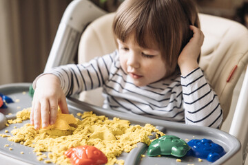 Cute little boy playing with kinetic sand. Development of fine motor skills. Early sensory education. Activities Montessori. Sensory plays at home.