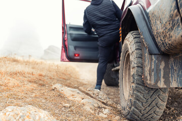 Bottom POV view male person driver open door of 4x4 awd suv vehicle on dirt gravel unpaved road in autumn at misty mountain top. Off road car mountain safari adventure nature trial journey concept © Kirill Gorlov