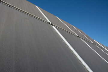 roof of a building covered with photovoltaic panels. Solar panels on the roof of the house ora...