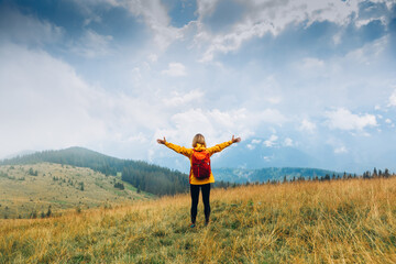 Cheering woman hiker open arms at fall mountains. Happiness Discovery Travel Destination Concept