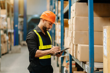 Storage worker in uniform and notepad,digital tablet in hands checks production. warehouse concept.
