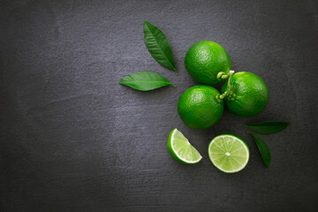 Group lime with sliced and green leaf on black dark background , top view , flat lay.
