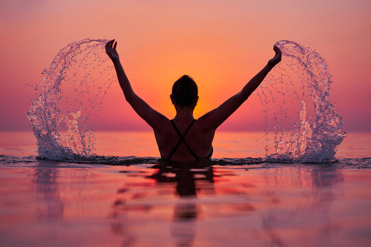 Young woman swimming in the sea on sunrise