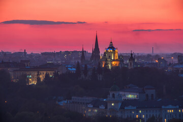 Fototapeta na wymiar Majestic sunset over Lviv city, Ukraine. St. George's Cathedral backlighted in the dusk. Silhouettes of spires of St. Elizabeth Church. Picturesque fire sky