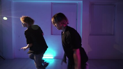 Two professional twin dancers dancing  modern dance in the dance hall in neon light