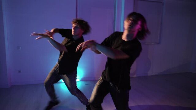 Two professional twin dancers dancing  modern dance in the dance hall in neon light