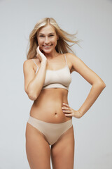 Young pretty slim 35 years old woman in cotton inner wear isolated over gray studio background....