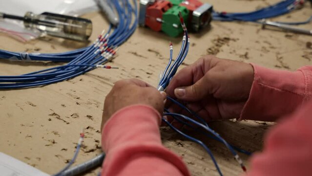 A person working at a table wrapping and coiling wires.