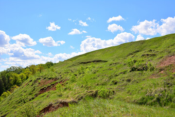 green hill with blue sky and white clouds on background